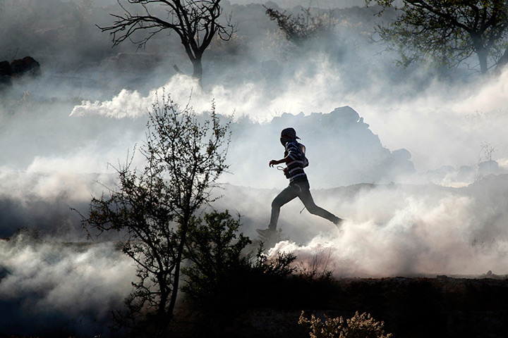 Gaza Strip: A Palestinian demonstrator runs through a cloud of tear gas